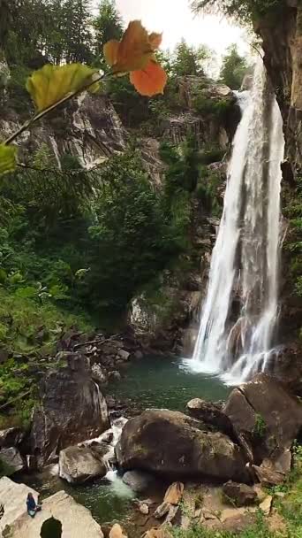 緑色の花崗岩と緑豊かな森の間の滝 ターコイズ水と岩の上に座っている少女の間のゆっくりとした動きのショット — ストック動画
