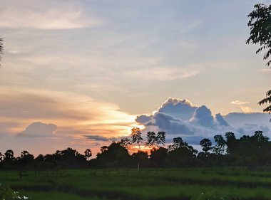 Güzel bulutlu gün batımı ve deniz manzarası. Gökyüzü öğleden sonra pembe ve altındır..