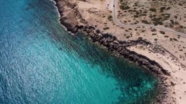 4K insansız hava aracı videosu kristal berrak sular ve kayalarla kıyı şeridi üzerinde uçuyor.