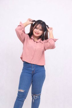 Güzel, havalı, saçları olan, gülümseyen yüzüyle kameraya bakan ve beyaz arka planda çalışan, reklamcılık yapan güzel bir kız.