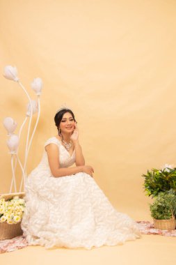 Zarif bir kadın poz verir, rahat rahat rahat oturur, merdivenlerden yukarı bakar, göğsünü tutar, güzel bir iç mekan fotoğrafı giyer. Evlilik Ulusal Gelin Stüdyosu