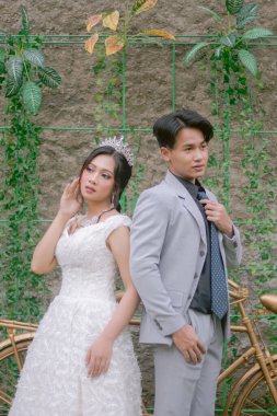 Bir çift kadın ve erkek, parkta çekilmiş bir fotoğrafta güzel elbiseler giymiş romantik ve kumruların karşısında zarif pozlar veriyorlar.