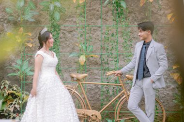 Zarif pozlar veren bir çift kadın ve erkek parkta çekilen bir fotoğrafta birbirlerine romantik ve sevgi dolu elbiseler giyiyorlar.