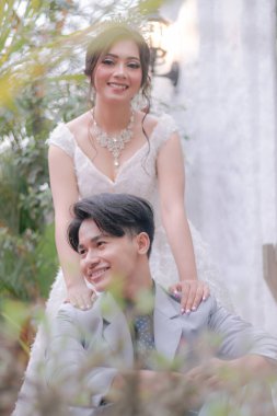 Bir çift erkek ve kadın zarif bir şekilde ayakta duruyor ve erkek gülümseyen romantik ve samimi bir şekilde parkta güzel elbiseler giyiyor.