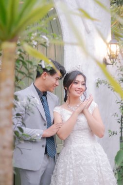 Zarif pozlarda bir çift kadın ve erkek romantik ve samimi bir kadına bakıyorlar bahçede güzel bir elbise giyiyorlar, milli gelin açık havada evleniyor.