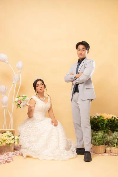 male and female couple woman sitting in formal poses standing relaxed smiling smiling each other laughing looking forward intimately indoor photo shot. couple wedding national bride studio