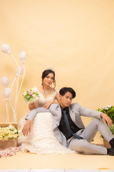 elegant male and female couple poses sitting relaxed smiling at each other looking forward intimately indoor photo shot. couple wedding national bride studio