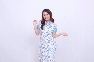 Modern Çin elbisesi giyen güzel, neşeli Asyalı kadın beyaz arka planda tek başına dans ediyor. Mutlu Çin Yeni Yılı