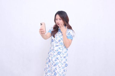 Çin malı mavi elbiseli genç Asyalı kadın Cheongsam 'ı telefonda kameraya bakarken hayal kırıklığına uğrattı.