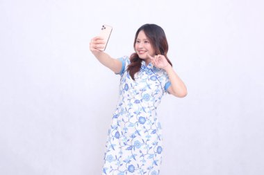 Çin malı mavi elbiseli genç Asyalı kadın Cheongsam 'ı telefonda kameraya bakarken hayal kırıklığına uğrattı.