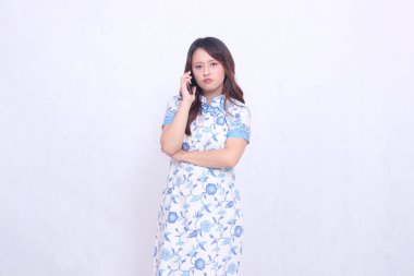 Çin malı mavi elbiseli genç Asyalı kadın Cheongsam 'ı telefonda kameraya bakarken hayal kırıklığına uğrattı.