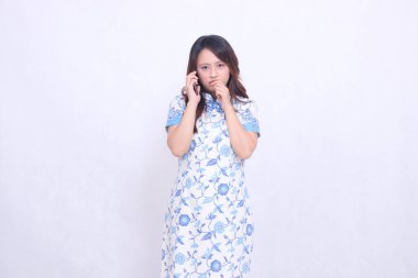 Çin malı mavi elbiseli genç Asyalı kadın Cheongsam 'ı telefonda kameraya bakarken hayal kırıklığına uğrattı.