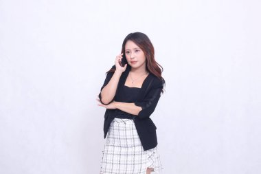 Güzel Endonezyalı kadın 20 'li yaşlarda resmi ofis siyah cep telefonu cihazıyla telefonda gülümsüyor ve beyaz arka plan tanıtımı için bir tablet taşıyor.