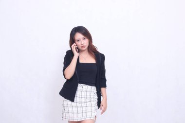 Endonezyalı güzel bir ofis kadını. 20 'li yaşlarda. Telefonda, tanıtım amaçlı cep telefonu kremi renginde, izole edilmiş beyaz bir arka plan.