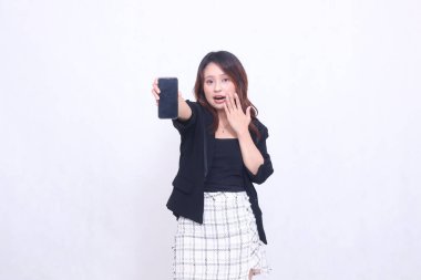 20 'li yaşlarda Endonezyalı güzel bir ofis kadını, şaşkınlık ifadesi, tanıtım amaçlı cep telefonu ekranında promosyon için promosyon, beyaz arka planda izole edilmiş.