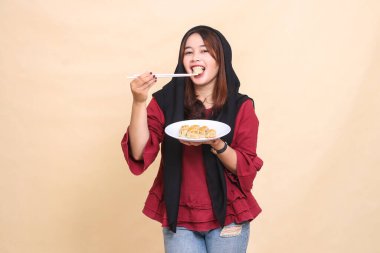 Güzel, olgun bir Asyalı kadın kırmızı bir başörtüsü takıyor, gülümsüyor, gamzeleri ısırıyor, çubuklar kullanıyor ve kameraya bakan gamzeli bir tabak taşıyor. Aşçılık içeriği için kullanılır