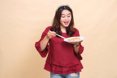 Kırmızılı güzel Asyalı kız içinde gamsum (Çin yemeği) ve çubuklu sos bulunan bir tabak taşırken mutlu oluyor. Gıda, sağlık ve yaşam tarzı içeriği için kullanılır