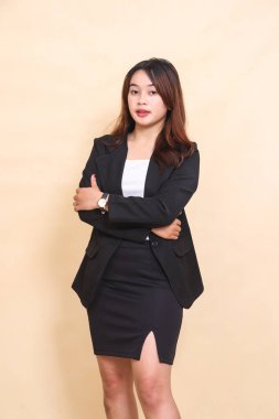 Güzel genç Asyalı yönetici kadın sağ tarafta zarif bir şekilde duruyor ve kameraya bakıyor kollarını kavuşturmuş, ticari, kurumsal ve iş dünyası için sarı arka planda yarım vücut portresi