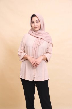 Başörtülü Müslüman kadın göbeğin önünde gülümseyerek duruyor. Reklam, moda, yaşam tarzı için güzel kadınlar.