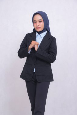 Asyalı, mavi gömlekli, tesettürlü, dik açılı bir kadın hoş geldin jesti olarak gülümsüyor. Güzel Müslüman kadınlar iş, teknoloji ve moda kullanır.