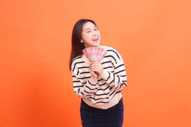 İki eli birkaç rupia tutarken mutlu bir ifadeye sahip Endonezyalı bir kadın. moda, iş ve finans konsepti için