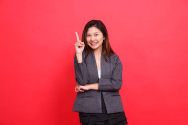 Kollarını kavuşturmuş, gri ceketli ve kırmızı arka planda siyah etekli, neşeli Asyalı bir ofis kızının jesti. kurumsal kavramlar, yayınlar ve reklamlar için
