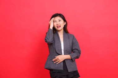 Asyalı ofis kızının baş dönmesi ve baş ağrısı ifadesi. Gri ceket ve kırmızı etek giyiyor. Sağlık, iş ve reklam kavramları için