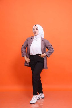 Güzel, samimi, Müslüman, Asyalı kadın modelin, şık bir tesettüre bürünmüş portresi, izole edilmiş turuncu bir arka plan giyer. Moda kavramı, güzellik, arkadaşlık