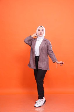 Endonezya 'nın güzel Müslüman kadın modelinin tam boy portresi profesyonel samimi poz beyaz ofis elbisesi giyerek turuncu stüdyo arka planı. Moda kavramı, güzellik, arkadaşlık