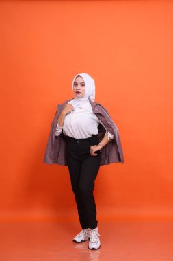 Endonezya 'nın zarif kadın portresi gömlek ve cep elbisesi ile turuncu stüdyo arka planına sarılı. Moda kavramı, güzellik, arkadaşlık