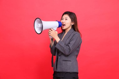 Endonezyalı ofis kadınının yüzü, kırmızı arka planda gri ceket ve etek giyen bir megafonla sağa doğru eğik bir şekilde bağırıyordu. Yayın, iş ve reklam kavramları için