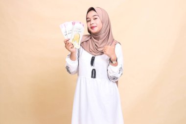 Güzel bir Asyalı Müslüman kadın portresi, tesettür takan, zarifçe gülümseyen, baş parmak hareketi yapan, hediye tutan veya bayram gününde forma giyen. Reklam, Kurban ve Ramazan için kullanılır.