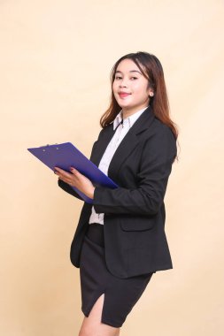 Endonezya 'nın güzel resmi yöneticisi zarif gülümsemeli olgun bir kız elinde bir panoyla kameraya poz veriyor, ticari, boş ve iş yeri için sarı arka planda 3' e 4 vücut portresi.