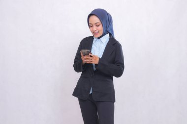 Endonezya ofis yöneticisi, tesettürlü, gülümseyen, cep telefonu kullanan bir kadın. İş, finans ve teknoloji içeriği için kullanılan mavi gömlekli güzel Müslüman kadın