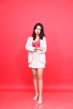 Endonezyalı genç bir kadının vücut portresi. Günlük koltuk altı, krem rengi spor ceket giyiyor. İçerik materyalleri, afişler ve reklamlar için izole kırmızı arkaplan.