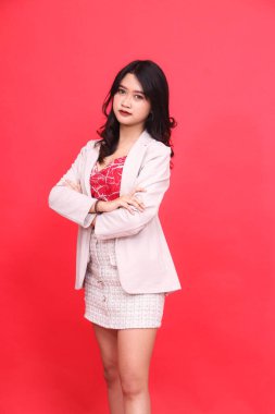 Sol tarafta Endonezyalı zarif genç bir kadının portresi krem renkli bir ceket giyiyor. İçerik materyalleri, afişler ve reklamlar için izole kırmızı arkaplan.