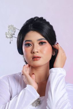 Endonezyalı genç bir kadının modern Cava geleneksel giysileri içinde beyaz bir stüdyo arka planında beyaz kadife bir gelin kebaya 'sı. Reklam içeriği, romantizm, güzellik, moda için