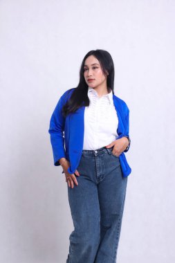 Endonezya 'nın genç ve güzel ofis hanımı resmi mavi takım elbise giyiyor samimi duruyor, elleri kalçaları ve pantolon cepleri tutuyor. Şirket, güzellik ve iş içeriği için