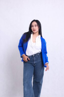 Endonezya 'nın güzel, genç, seksi ofis hanımı resmi mavi takım elbise giymiş elinde pantolon ve ceketle zarif bir şekilde duruyor. Şirket, güzellik ve iş içeriği için