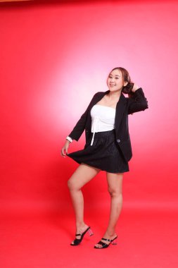 Kariyer ofisindeki olgun Asyalı kadının tam portresi. Siyah bir takım elbise giymiş, arkasında bir etek ve saç tutuyor. Şirket, moda, ticari içerik ve kurumsal içerik için.