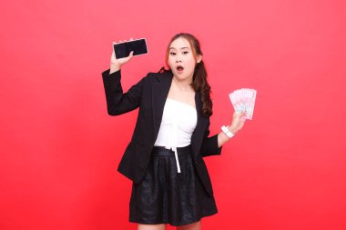 Siyah takım elbise giyen Asyalı genç bir kadının jesti. Rupiah 'ın parasını ve akıllı telefonunu teknoloji, iş, reklam ve finansal içerik için tutuyor.