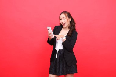 Genç Endonezya 'lı, neşeli, siyah takım elbiseli bir kadının jesti. Ona dokunurken akıllı telefon kullanıyor. Teknoloji, iş, reklam ve finansal içerik için.