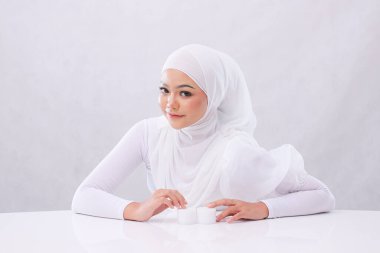 Güzel genç kadın peçeli gülüşünün portresi beyaz arka planlı günlük yüz bakımı için beyaz masadaki el kamerasına bakın. Yüz bakımı, mükemmel cilt.