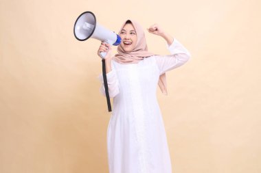 Asyalı kız tesettürlü, sağ tarafa eğimli, açık sözlü, bağıran, gülümseyen, hoparlör tutan ve yumruklarını yukarı doğru sıkan. Teknoloji, yayın ve tanıtım konsepti