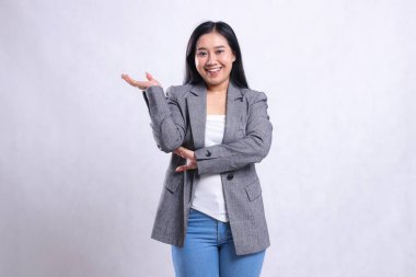 Gri ceketli ve beyaz arka planda tek başına duran kot pantolon giyen güzel, genç ve neşeli kollarını kavuşturmuş bir kadının ifadesi. Reklam içeriği, moda, afiş, dergi