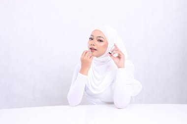 Çekici makyaj dudakları Güzel genç kadın Asya tesettüre zarif bir bakış kamera eline ruj sürerek izole edilmiş beyaz arka plan. Kozmetik reklam konsepti, dudak rengi, ruj modeli