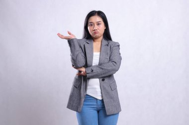 Asia 'nın kollarını kavuşturup gri takım elbise ve beyaz arka planda tek başına duran kot pantolon giyen güzel genç bir kadının ifadesi. Reklam içeriği, moda, afiş, dergi