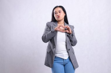 Asia 'nın öpüşen güzel yetişkin bir kadının el öpme ifadesi. Gri takım elbise ve beyaz arka planda izole edilmiş kot pantolon giyiyor. Reklam içeriği, moda, afiş, dergi