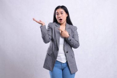 Gri takım elbiseli ve beyaz arka planda tek başına duran kot pantolon giyen genç ve güzel bayanların el işaretleri şaşırtıcıdır. Reklam içeriği, moda, afiş, dergi