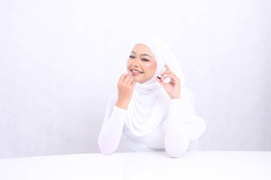 Cazibeli makyaj dudakları Güzel genç kız Asia peçe neşeli bir bakış kamera eline izole edilmiş beyaz arka plana ruj sürerken. Kozmetik reklam konsepti, dudak rengi, ruj modeli